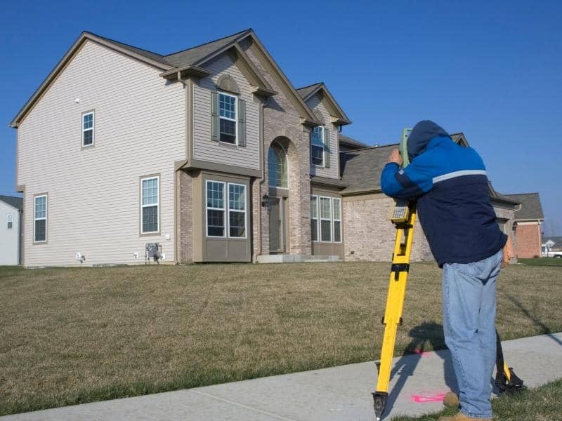 Surveyor measuring a residential property as part of estimating land survey cost